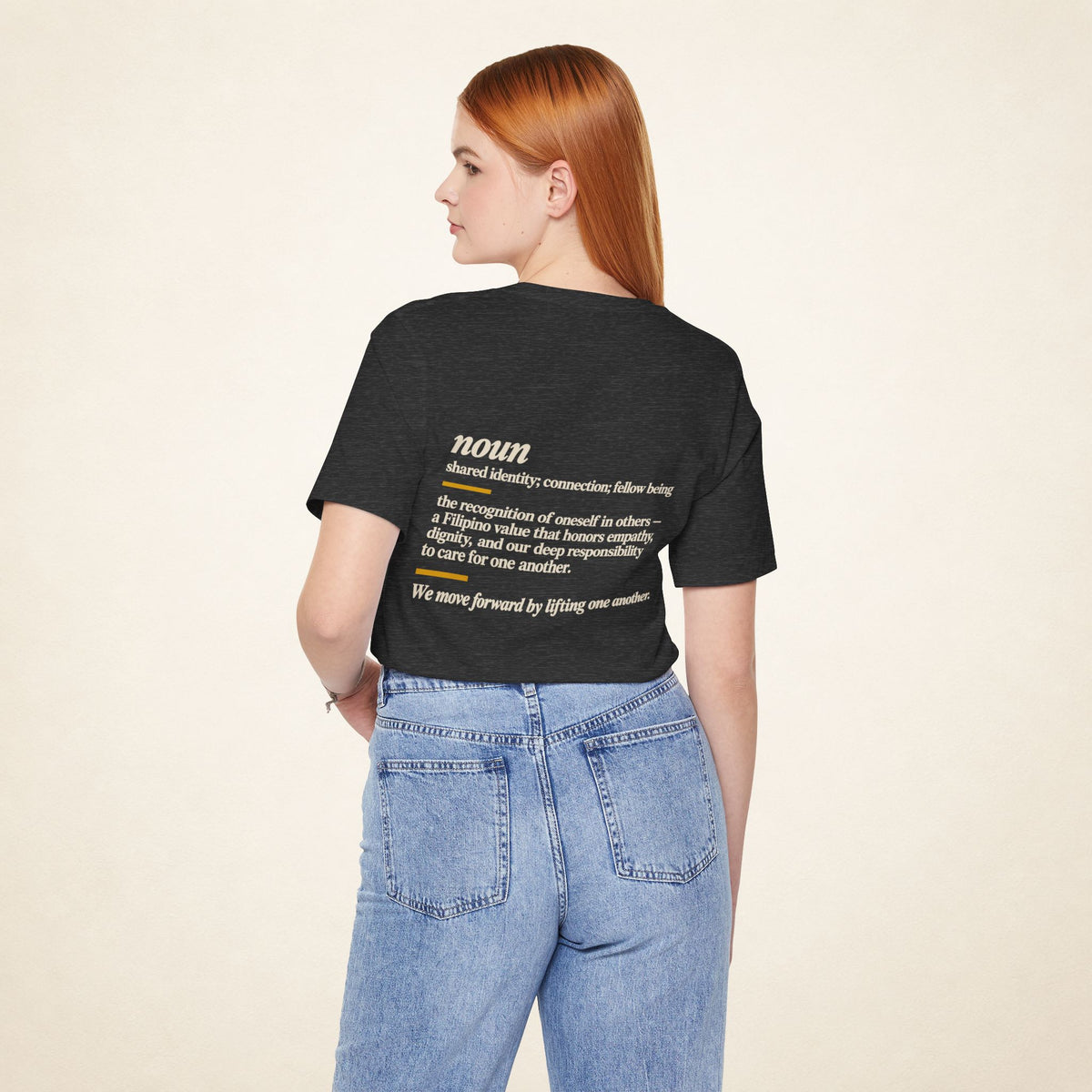 Model wearing the Dark Grey Heather KAPWA T-shirt from behind, showing the shared humanity back design.