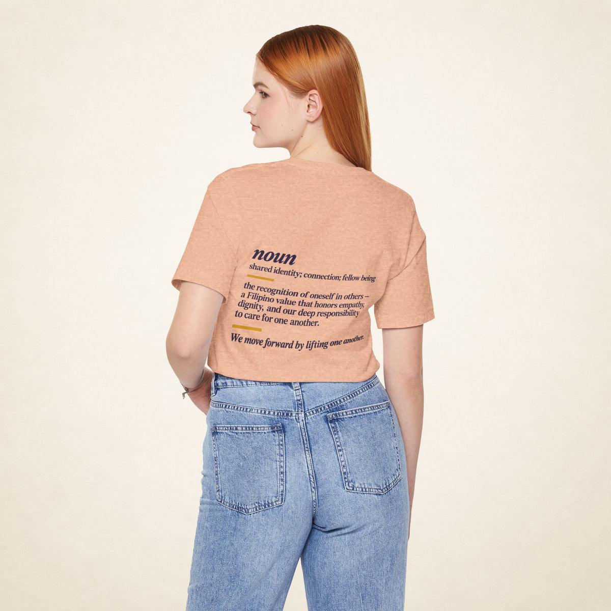 Model wearing the Heather Peach KAPWA T-shirt from behind, showing the shared humanity back design.