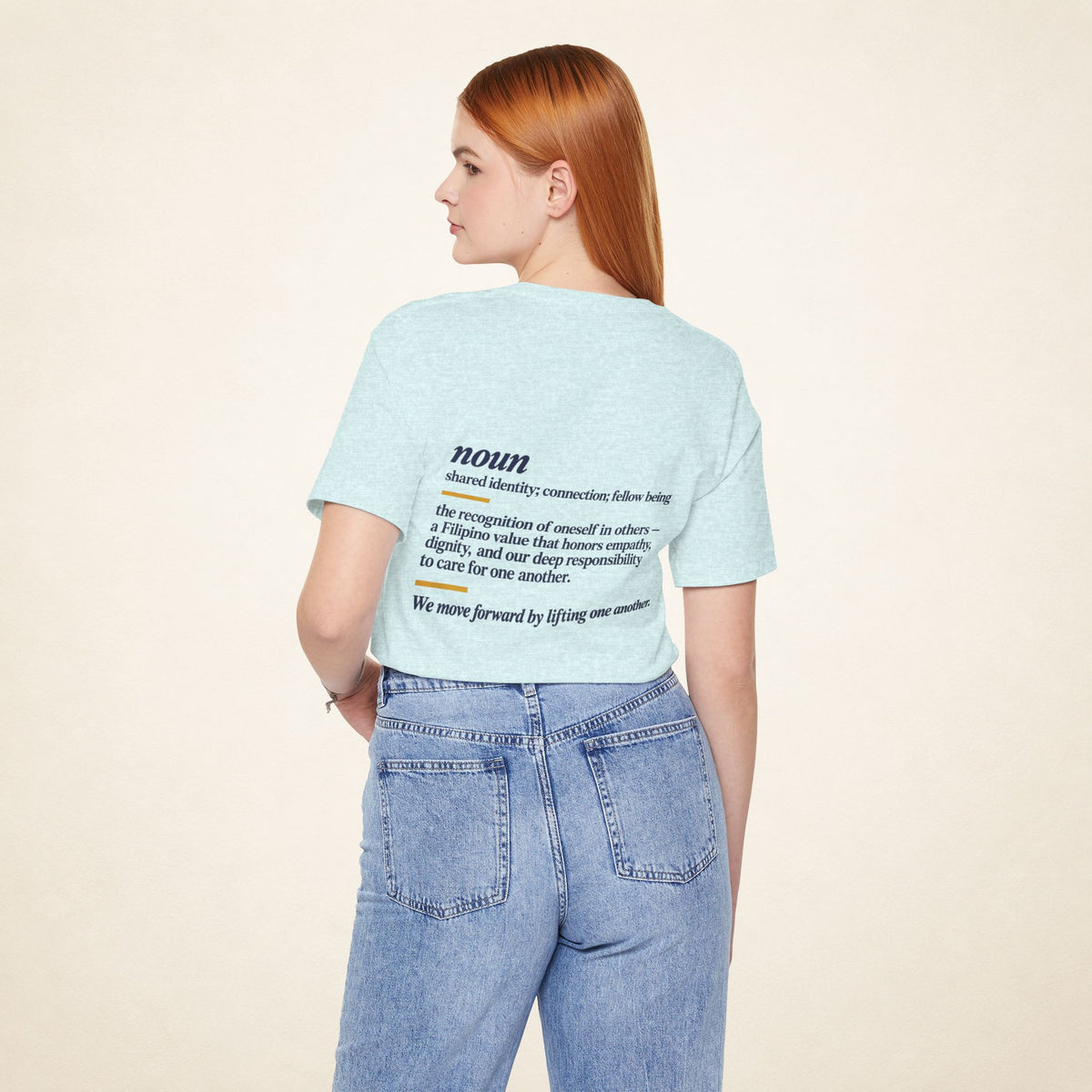 Model wearing the Heather Prism Ice Blue KAPWA T-shirt from behind, showing the shared humanity back design.