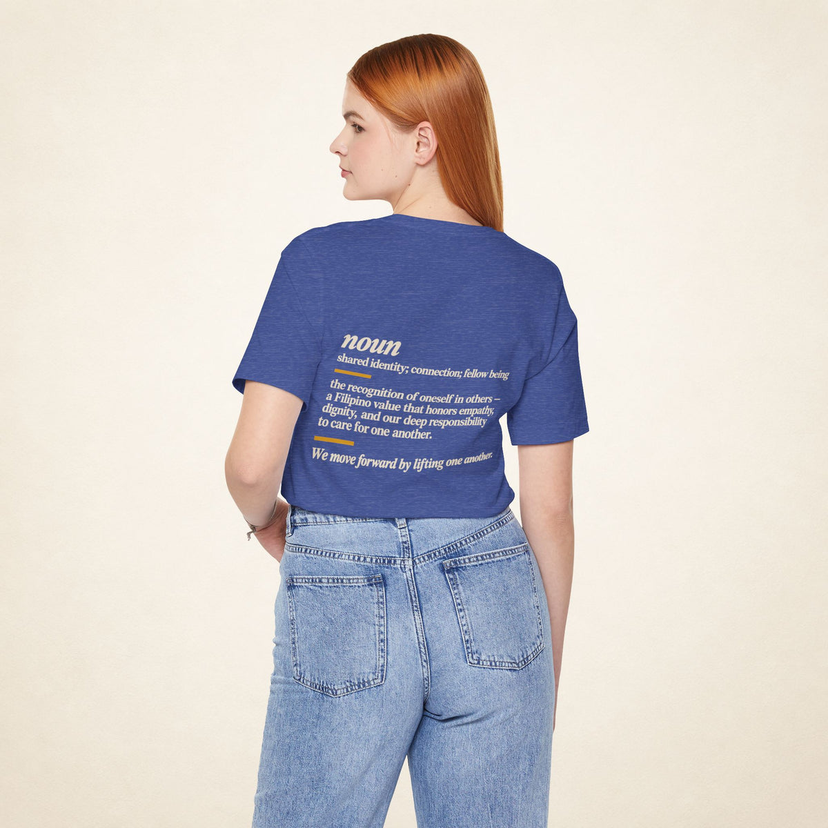 Model wearing the Heather True Royal KAPWA T-shirt from behind, showing the shared humanity back design.
