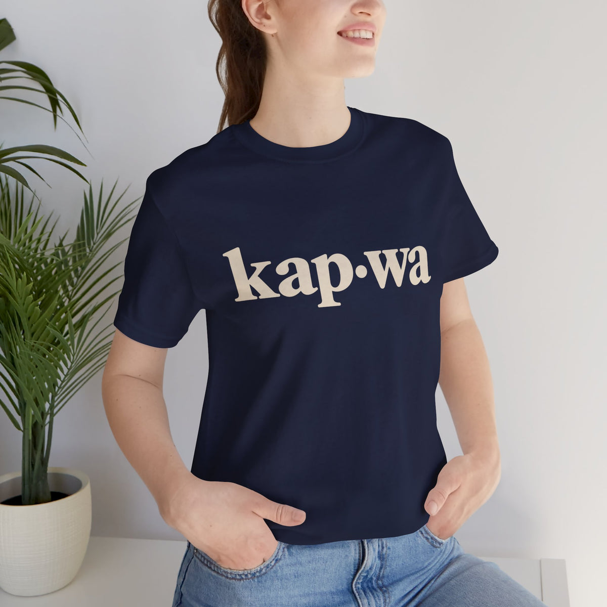 Seated model wearing the Navy KAPWA Filipino heritage tee, styled casually with the front graphic visible.