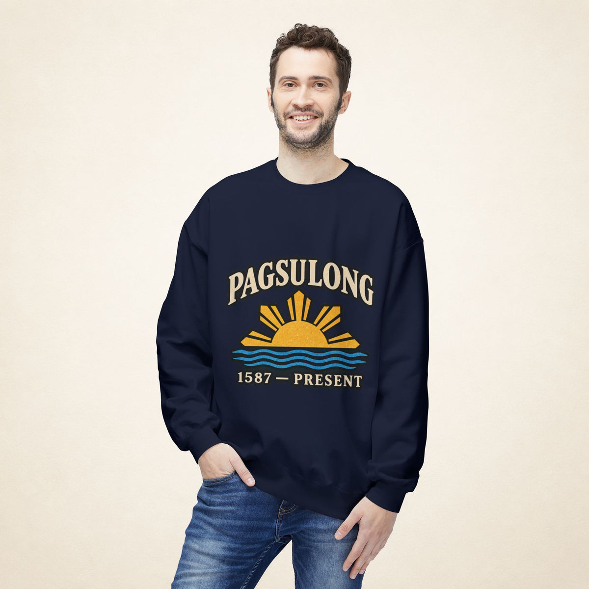 Male model wearing the navy PAGSULONG Filipino American heritage sweatshirt with the golden sun and blue waves artwork on the front, paired with blue jeans.